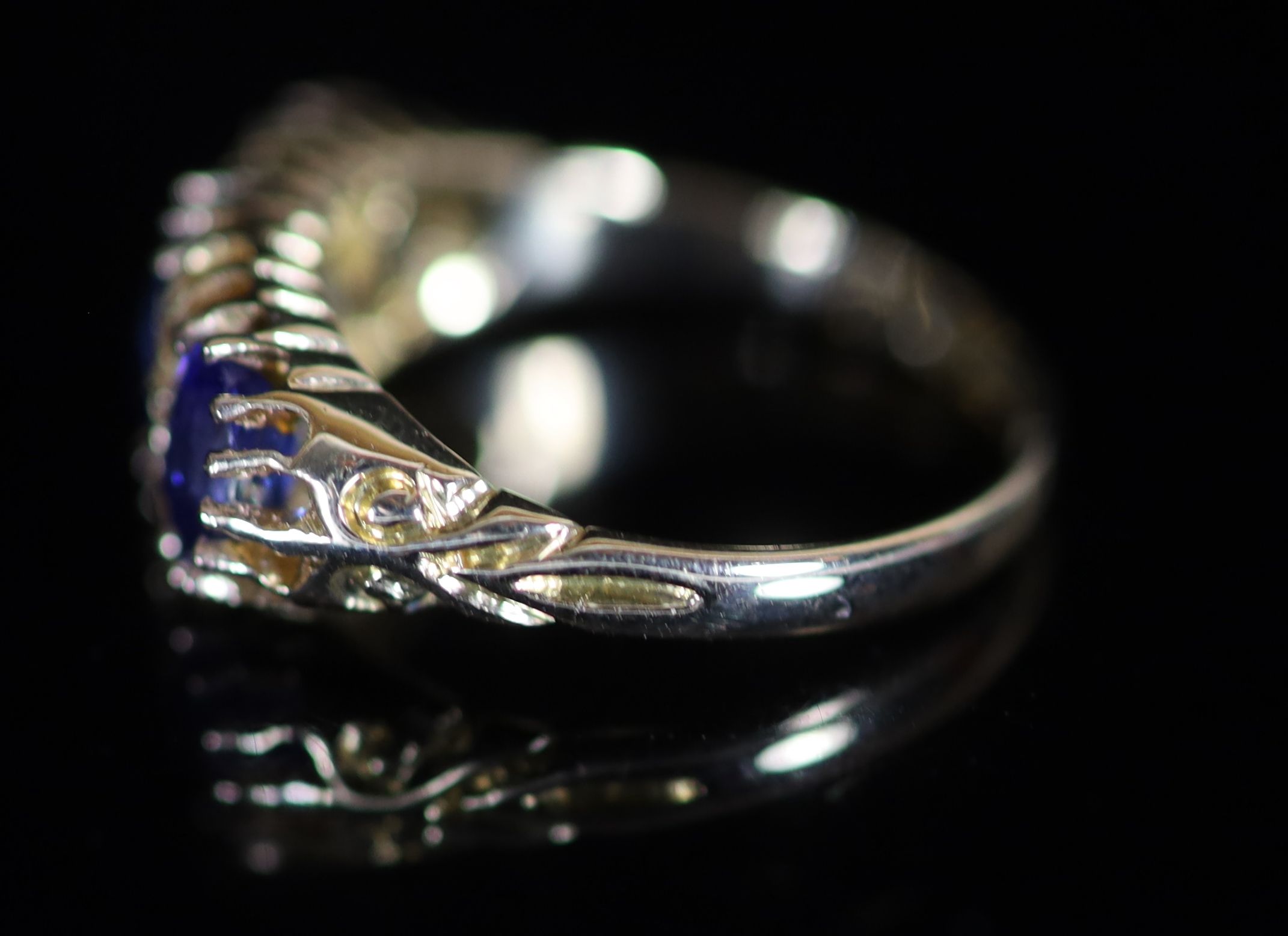 An Edwardian 18ct gold and three stone sapphire set half hoop ring with diamond chip spacers